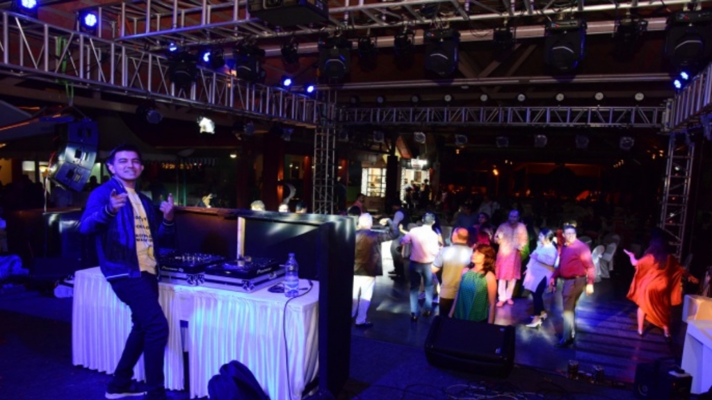 DJ playing behind deck with crowd dancing
